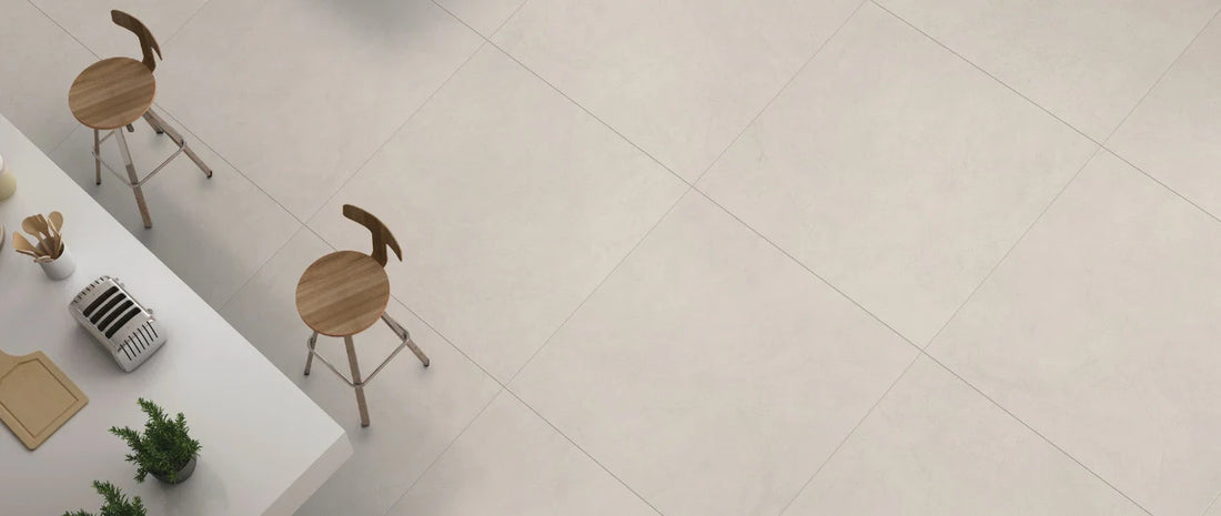 Light concrete-effect porcelain tiles used as a modern kitchen floor with large square slabs.