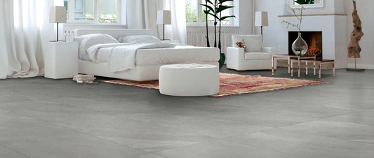 Light grey stone-effect porcelain tile flooring in a modern bright bedroom with white furniture and soft natural light.