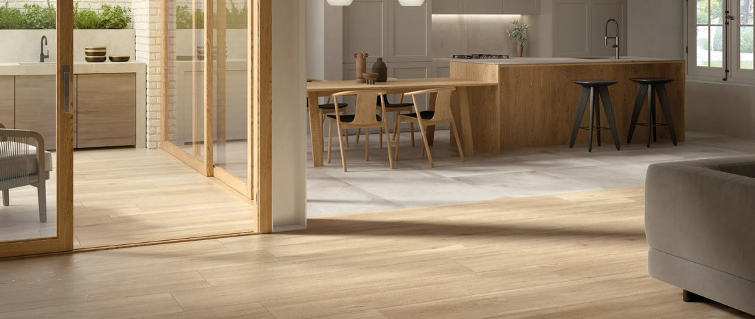Oak wood-effect porcelain tiles in 26x160 plank format in an open plan living area, zoned against light concrete-effect floor tiles in the kitchen and dining space
