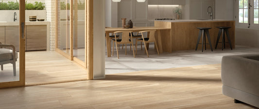 Oak wood-effect porcelain tiles in 26x160 plank format in an open plan living area, zoned against light concrete-effect floor tiles in the kitchen and dining space