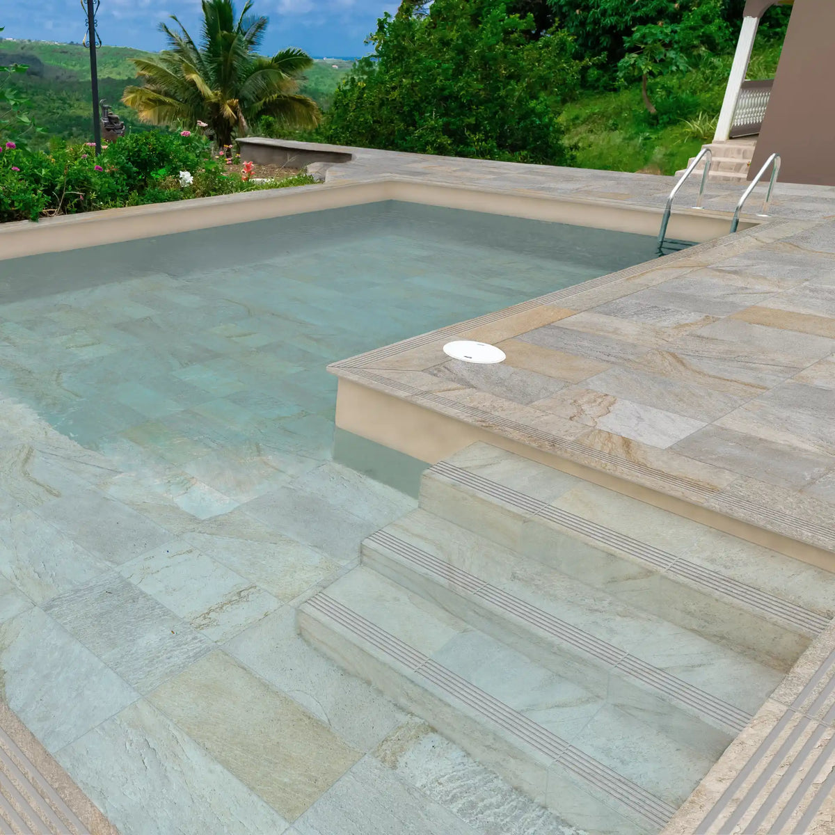 Outdoor swimming pool finished with grey-beige stone-effect porcelain tiles featuring R11 anti-slip rating and natural stone textures, Pietra di Serra