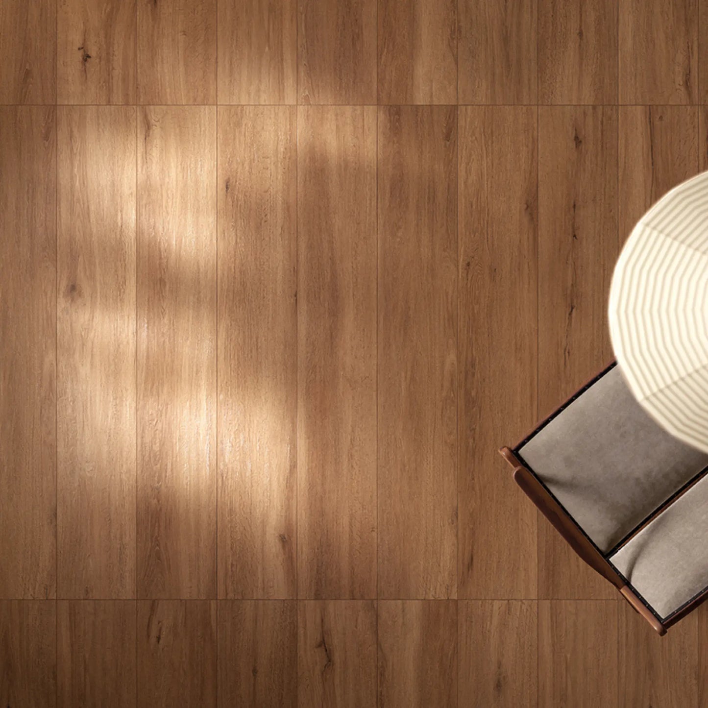 Warm oak wood-effect porcelain flooring seen from above, showing natural grain and soft light reflections – Firenze Ceraso
